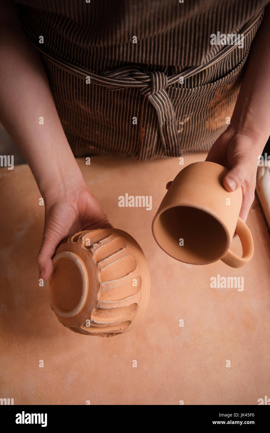 Mano di donna caucasica azienda coppa in ceramica e ciotola Foto Stock