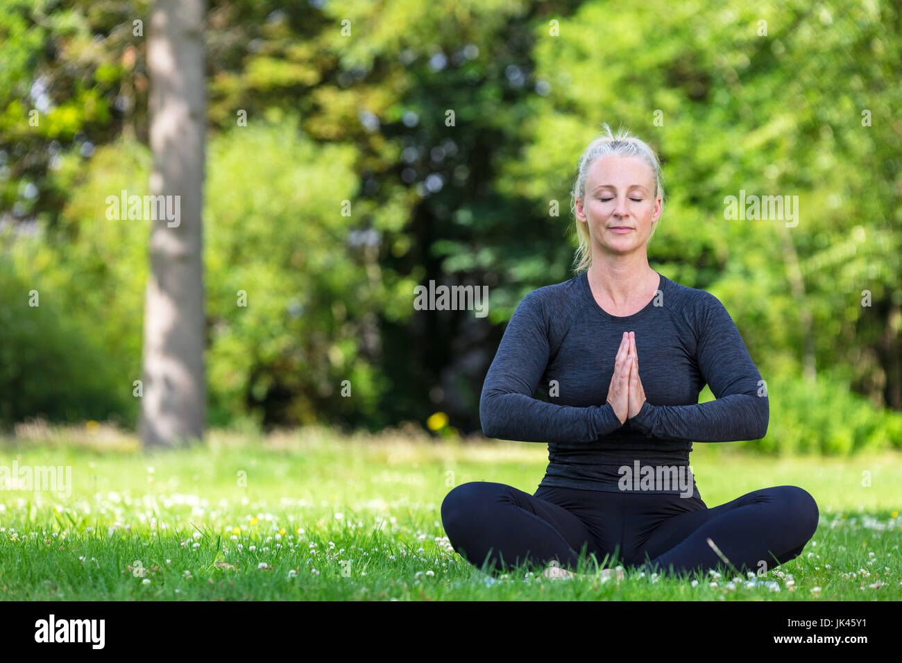 Coppia di mezza età montare donna sana pratica lo yoga al di fuori di una naturale tranquillo ambiente verde Foto Stock