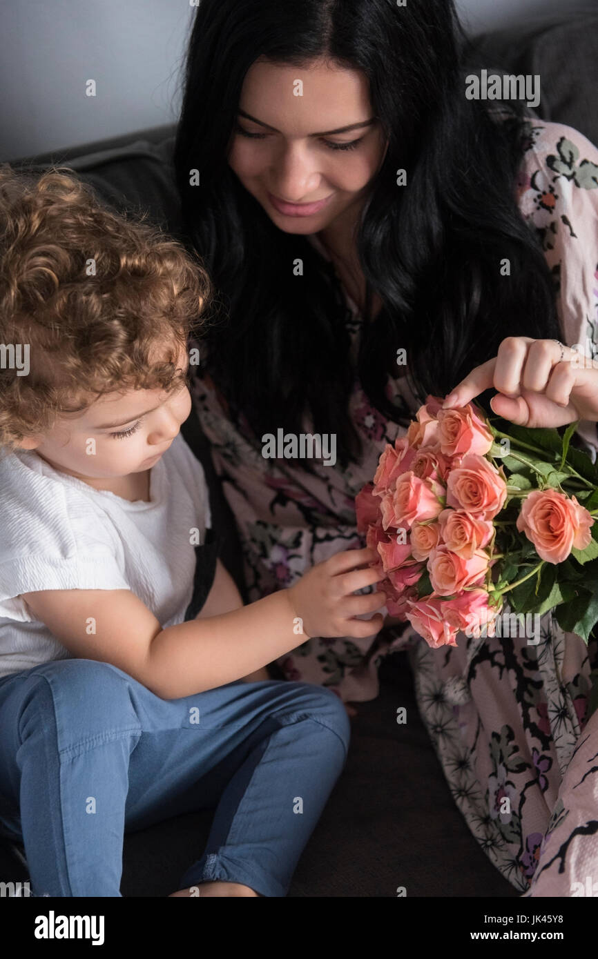 Madre caucasica seduto sul divano con il figlio esaminando i fiori Foto Stock