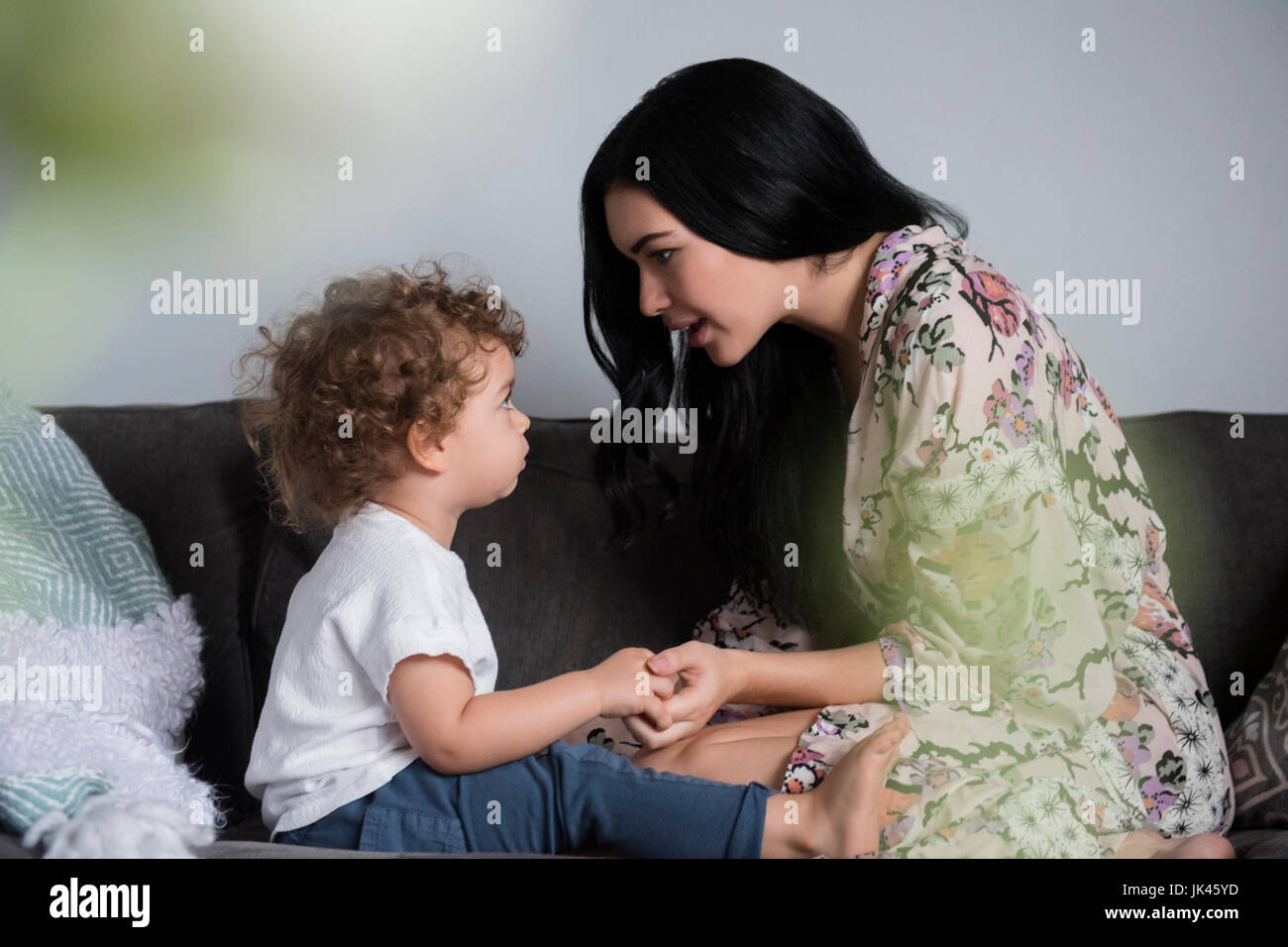 Madre caucasica seduto sul divano per mano e parlando con il figlio Foto Stock