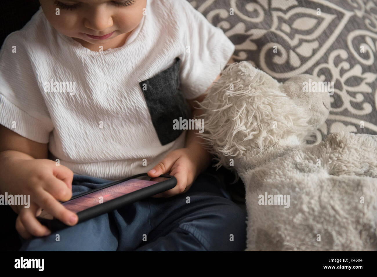 Ragazzo caucasico giocando con il telefono cellulare Foto Stock