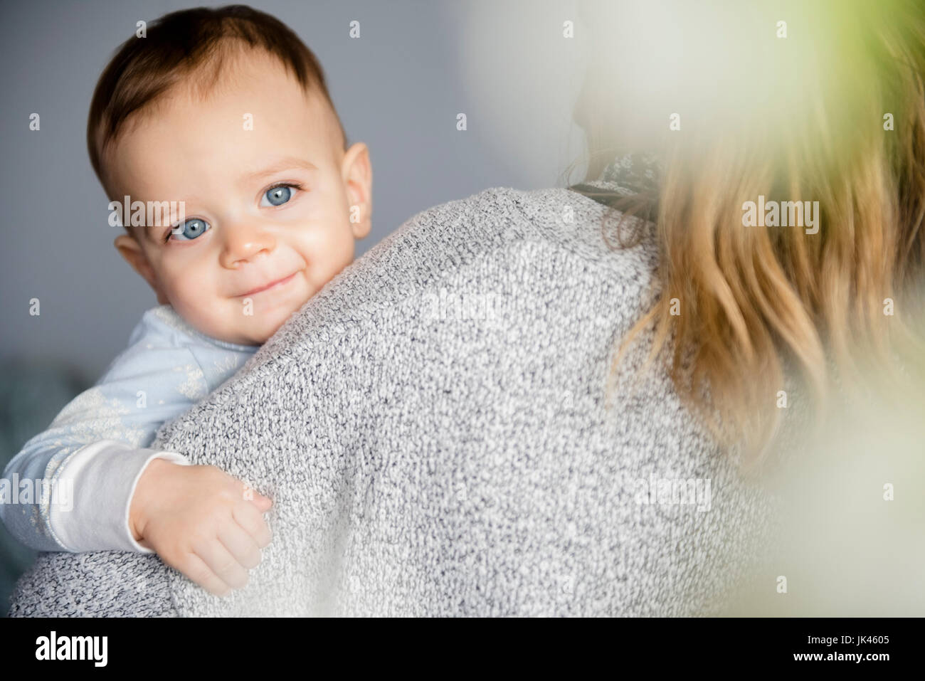 Caucasian baby boy sorridente sulla spalla della madre Foto Stock