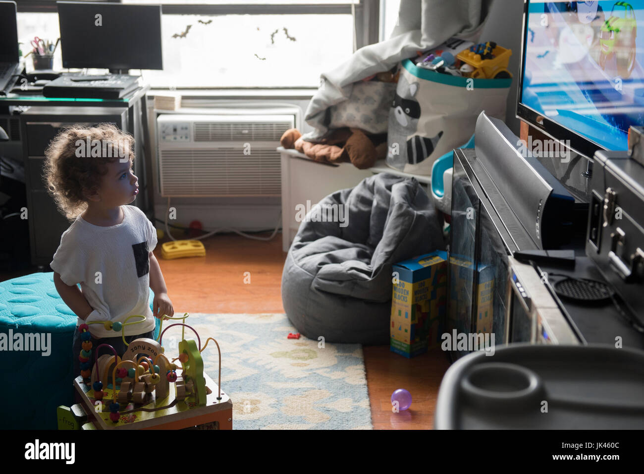 Ragazzo caucasico giocando in soggiorno con i giocattoli e guardare la televisione Foto Stock