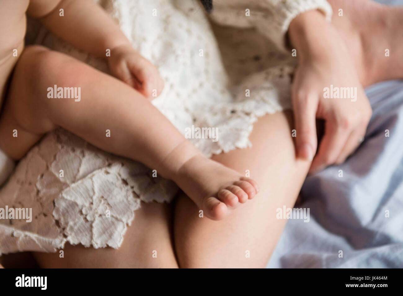 Gamba di soggetti di razza caucasica bambino seduto sulle ginocchia della madre Foto Stock