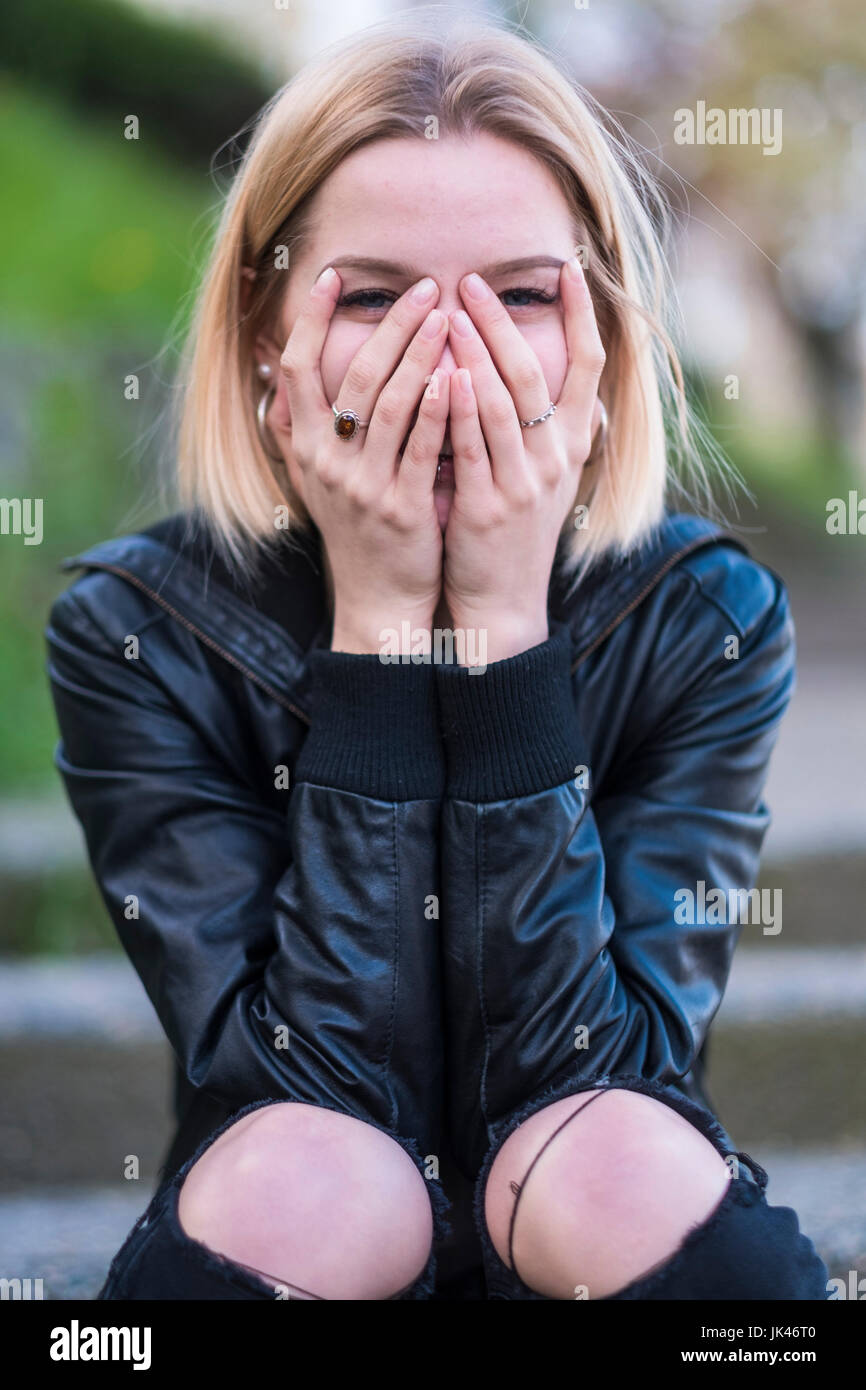 Ridendo donna caucasici che ricopre la faccia con le mani Foto Stock
