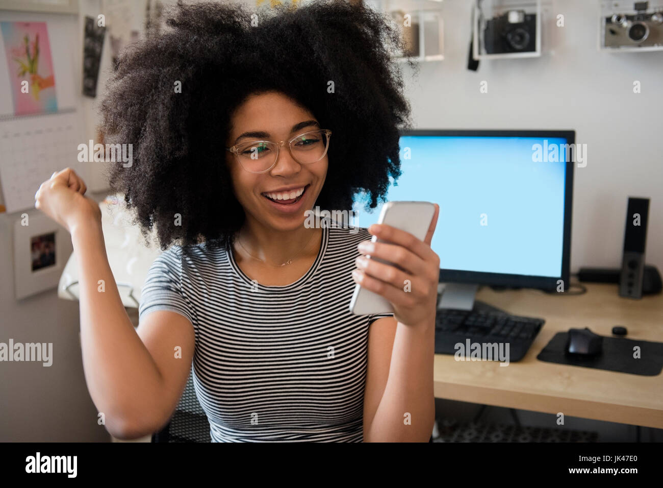 African American donna sms sul cellulare e celebrando Foto Stock