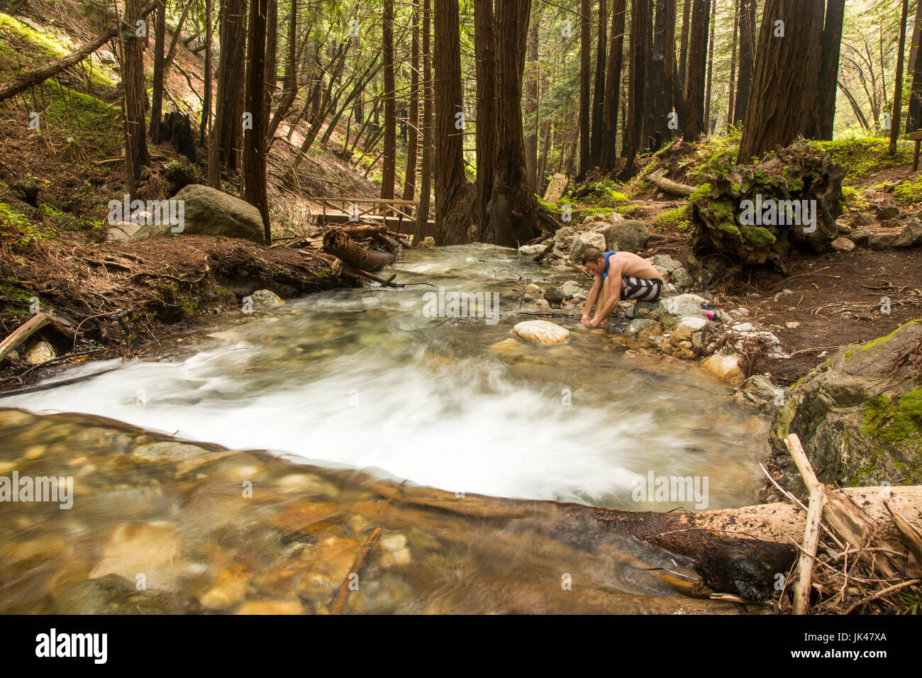 Uomo caucasico piede di lavaggio nella Foresta Fiume Foto Stock