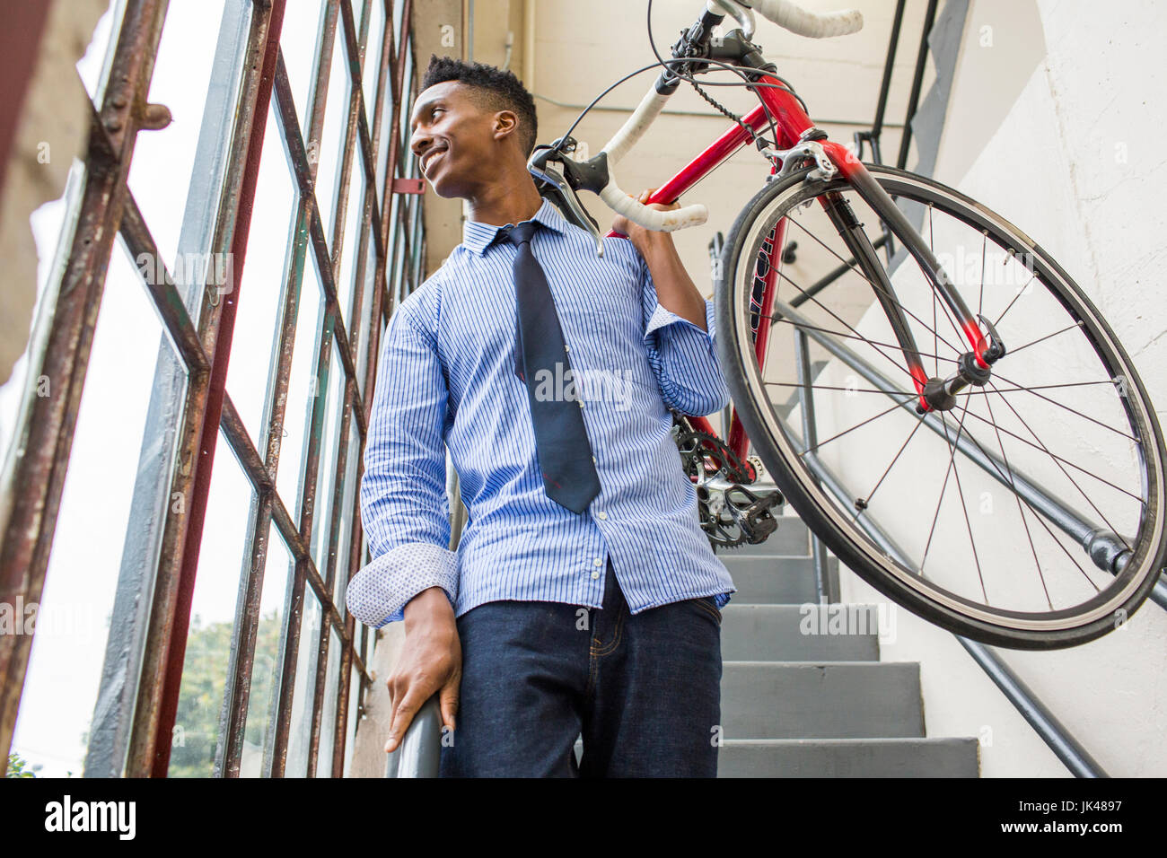 Imprenditore nero scala discendente che porta bicicletta Foto Stock