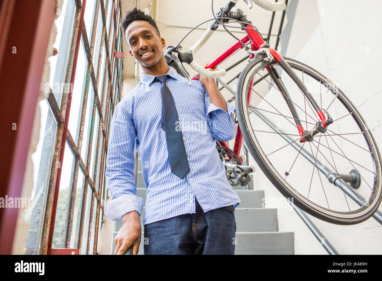 Imprenditore nero scala discendente che porta bicicletta Foto Stock
