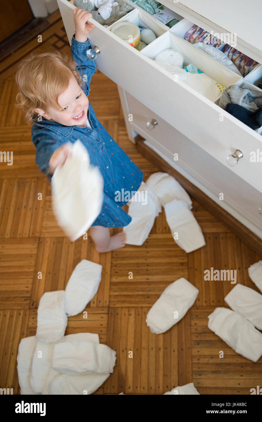 Ragazza caucasica gettando pannolini sul pavimento Foto Stock
