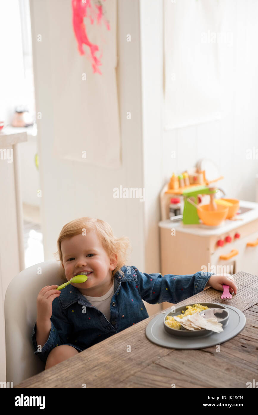 Ragazza caucasica mangiare con il cucchiaio e forchetta Foto Stock