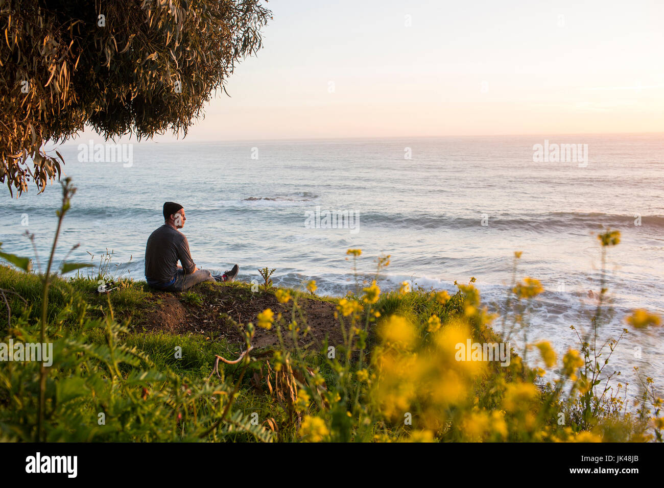 Uomo caucasico ammirando vista panoramica dell'oceano al tramonto Foto Stock