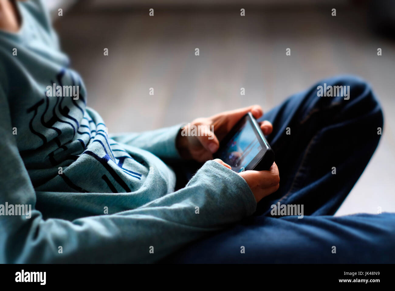 Ravvicinata di un ragazzo caucasico giocando con il telefono cellulare Foto Stock