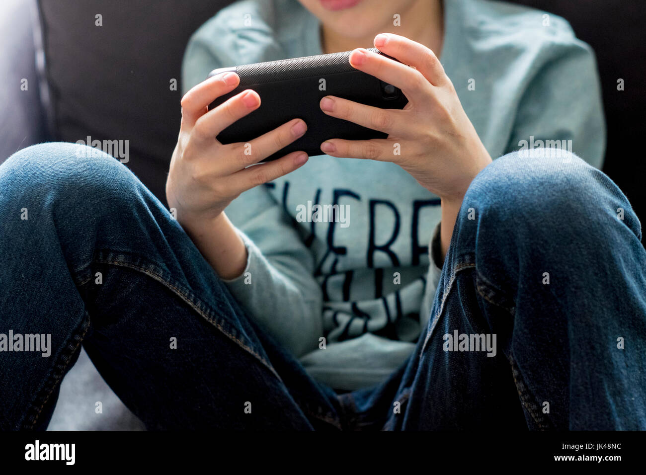 Ravvicinata di un ragazzo caucasico giocando con il telefono cellulare Foto Stock