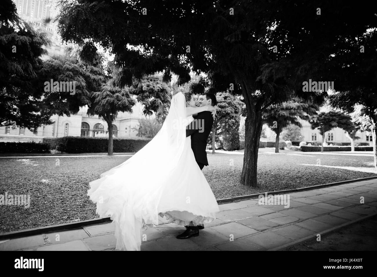 Fantastico matrimonio giovane passeggiate nel parco il giorno delle nozze. Foto in bianco e nero. Foto Stock