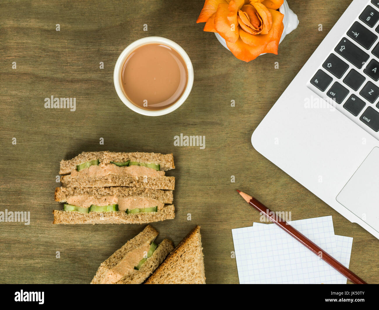 Salmone e cetriolo marrone sandwich di pane con una tazza di tè in corrispondenza di una stazione di lavoro computer Foto Stock