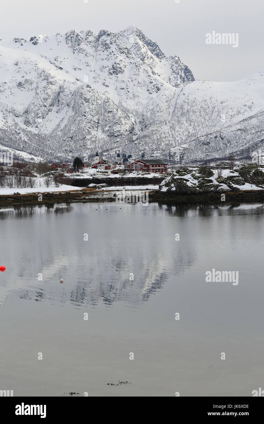 Cottage di rosso e sjohus-seahouse. Cappella bianca-penisola Sildpollnes visto da S.shore Sildpolltjonna bay. Kroktindan-Litlkorsnestinden mts.background Foto Stock