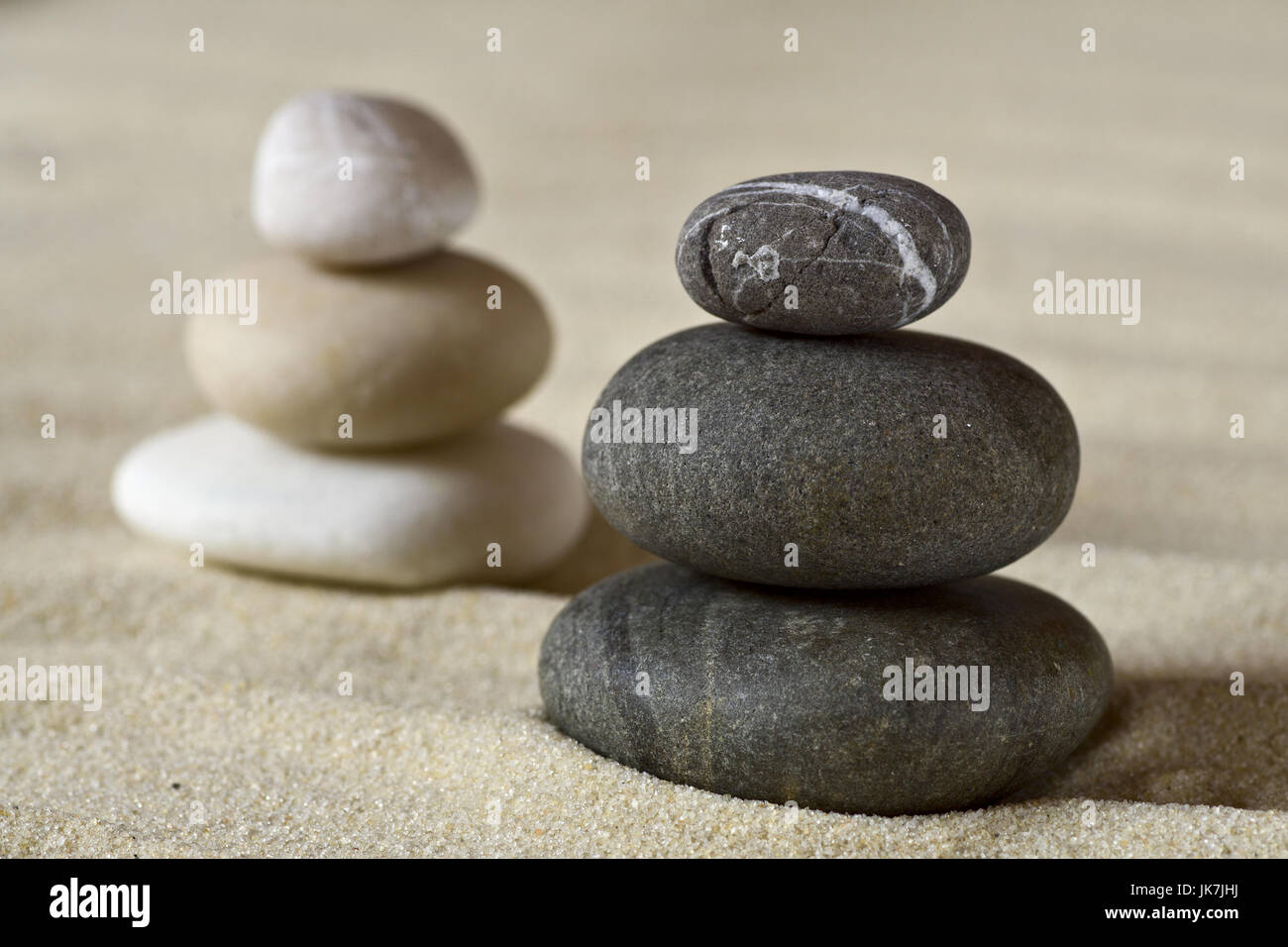 Dark e white mucchi di pietre equilibrato su una spiaggia di sabbia Foto Stock