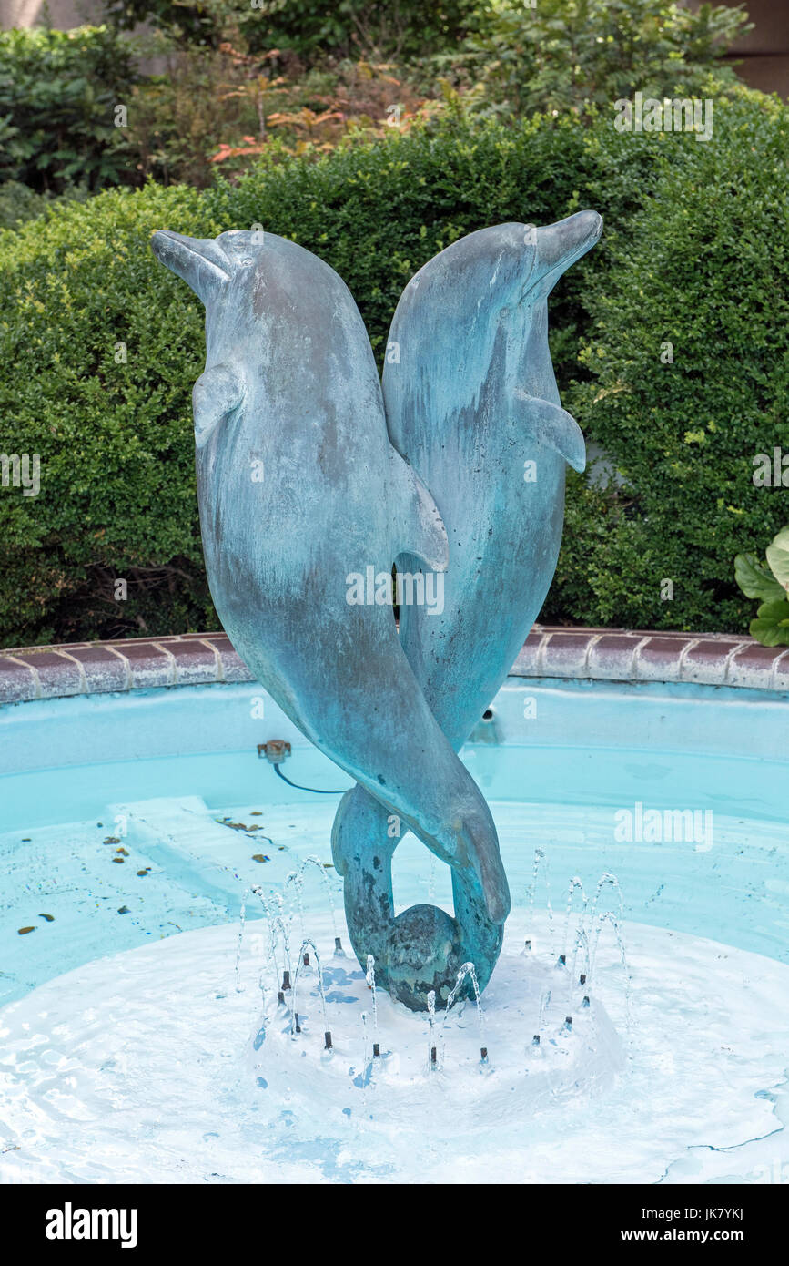 Fontana dei delfini - una funzione di acqua di due di bronzo dolphines equilibrato sul loro code al centro di un laghetto e circondato da 21 poli in acciaio schizzando w Foto Stock