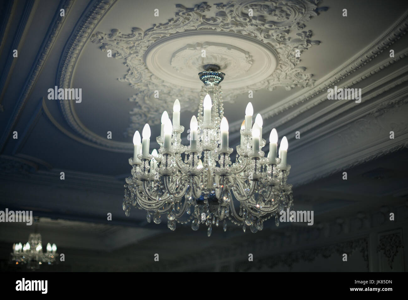Bellissimo ed antico lampadario di cristallo pende dal soffitto nelle ombre Foto Stock