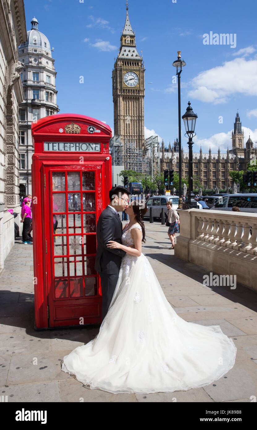 Un giovane cinese di posare per fotografie da un iconico telefono rosso scatola con il Big Ben in background come celebrano la loro luna di miele a Londra Foto Stock