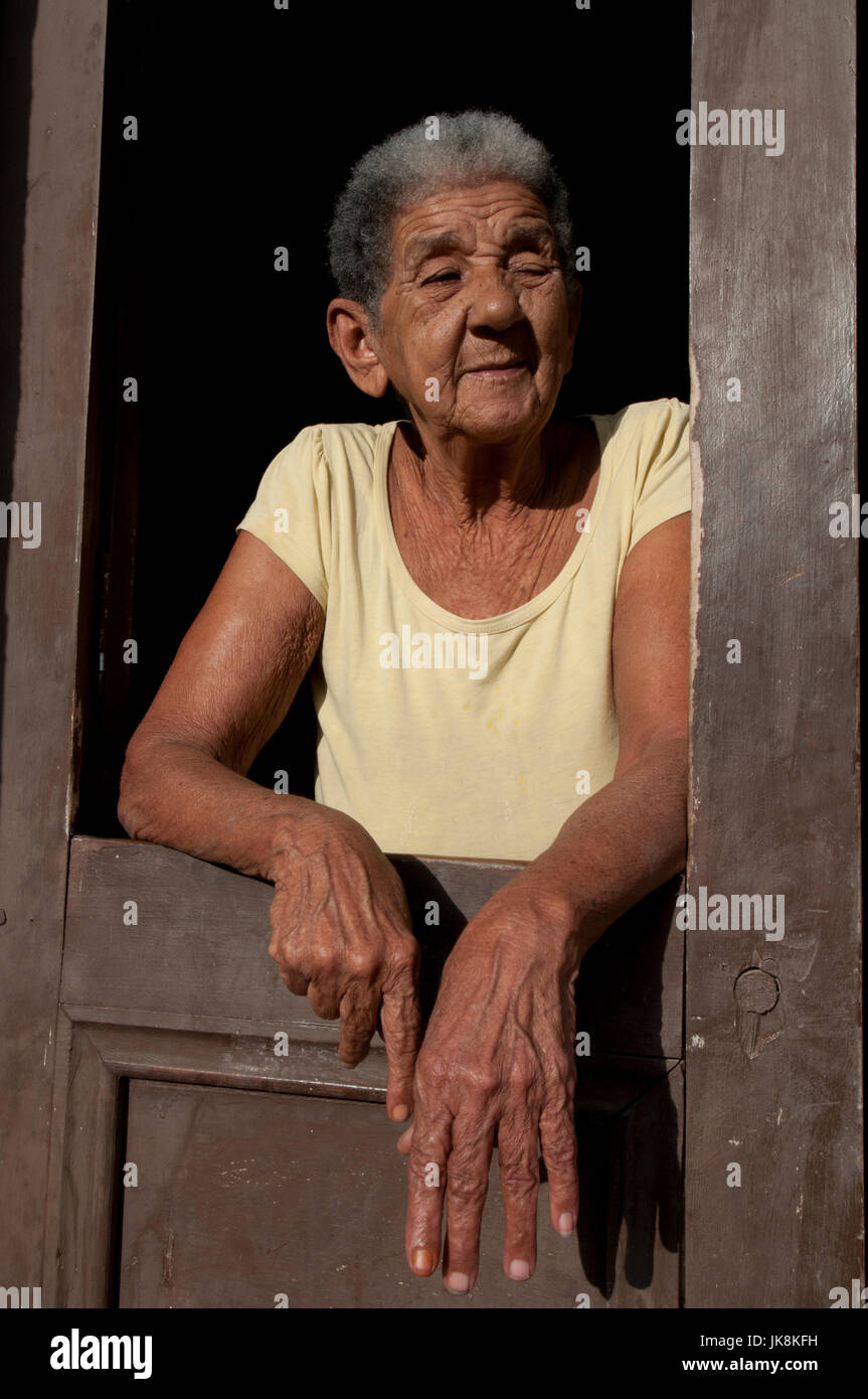 Anziana donna cubana in piedi nella sua porta in prima serata in Trinidad, Cuba Foto Stock