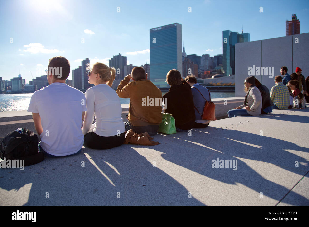 I giovani seduti in East River a Roosevelt Island con le Nazioni Unite in background in New York, NY, STATI UNITI D'AMERICA. Foto Stock