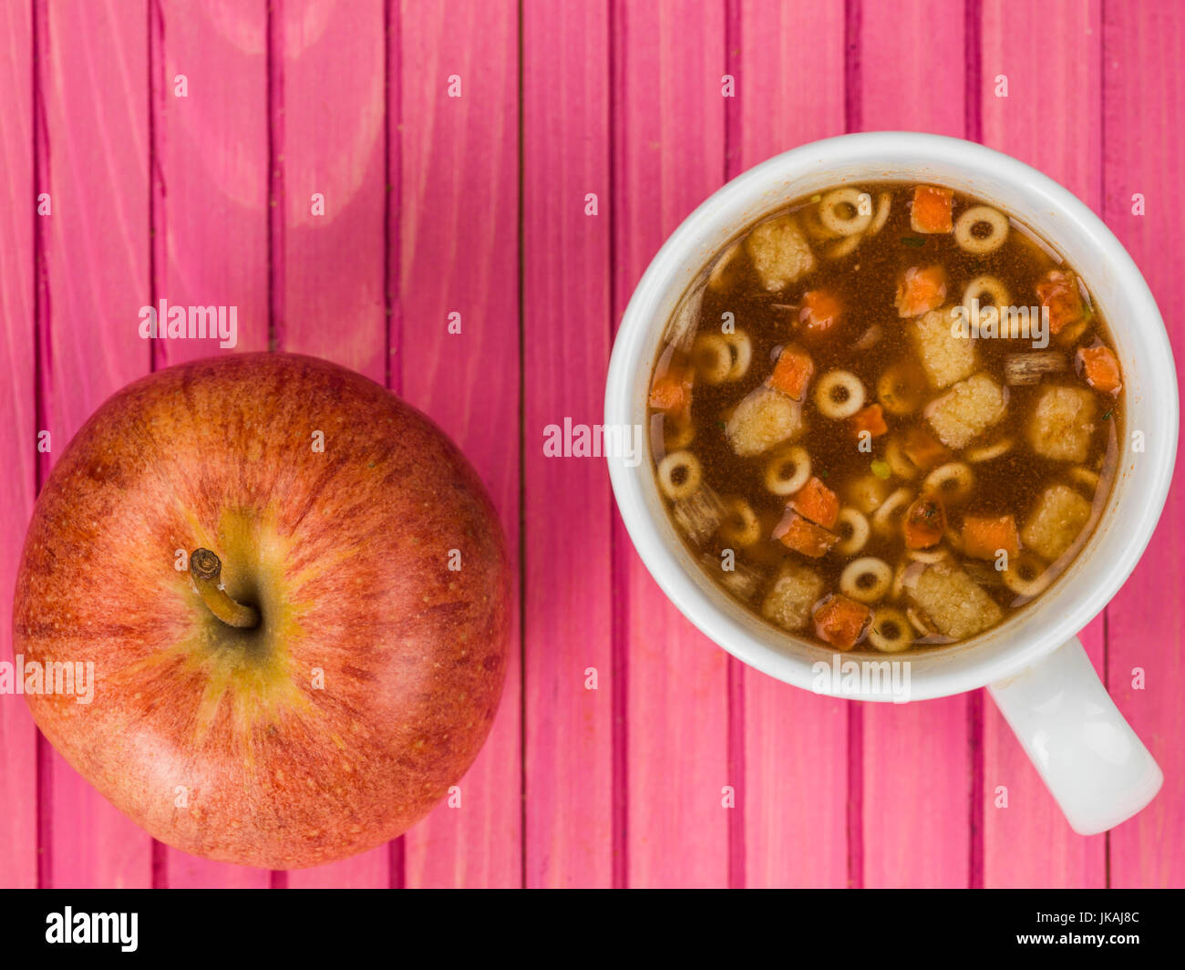 Tazza di instant minestrone contro una rosa di sfondo di legno Foto Stock