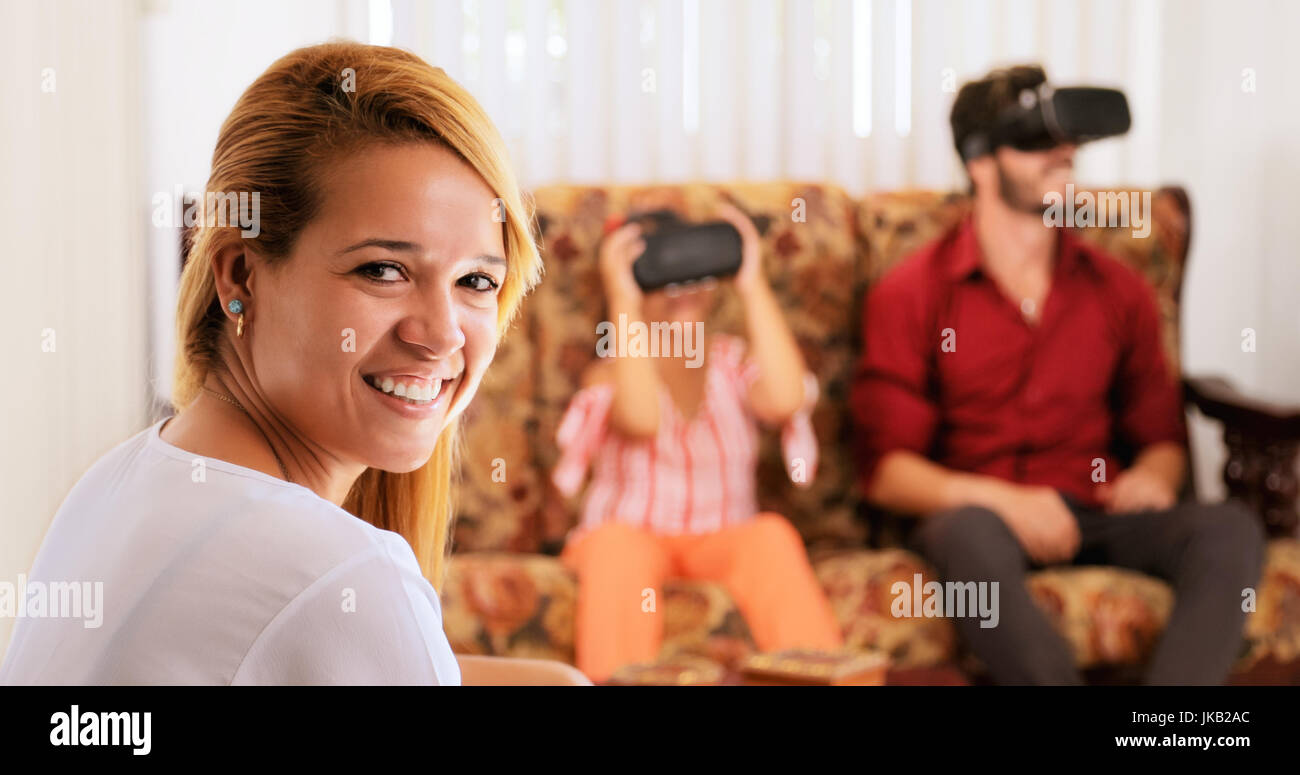 Felice famiglia bianco a casa. Padre ispanica, la madre e il bambino che gioca con la realtà virtuale gli occhiali. Ritratto di donna bionda sorridente alla fotocamera. Foto Stock