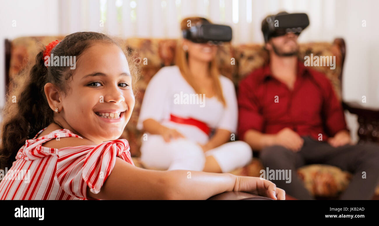 Felice famiglia bianco a casa. Padre ispanica, la madre e il bambino che gioca con la realtà virtuale gli occhiali. Ritratto di ragazza sorridente alla fotocamera. Foto Stock