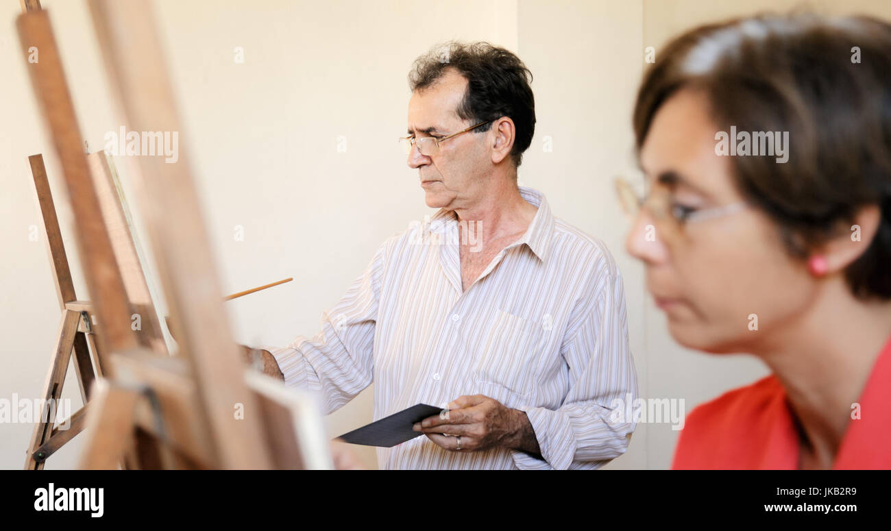 Le persone anziane a dipingere per hobby. Gruppo di anziani attivi presso la scuola d'arte. Felice ritirò l uomo e la donna che studia a scuola Foto Stock