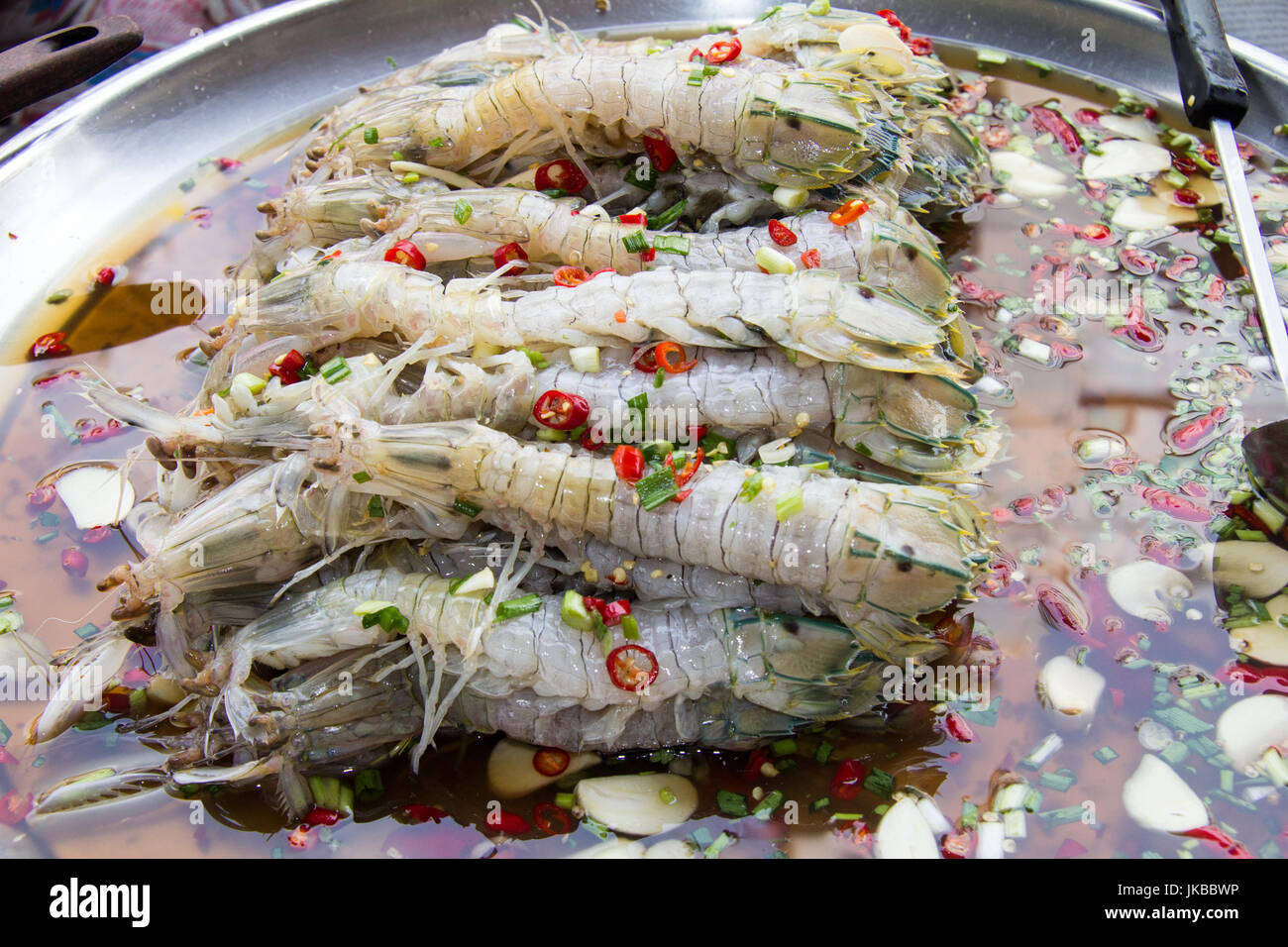 Piastra di materie di gamberi con aglio e peperoncino Salsa per la vendita di cibo di strada fornitore, Chinatown, Bangkok, Thailandia Foto Stock