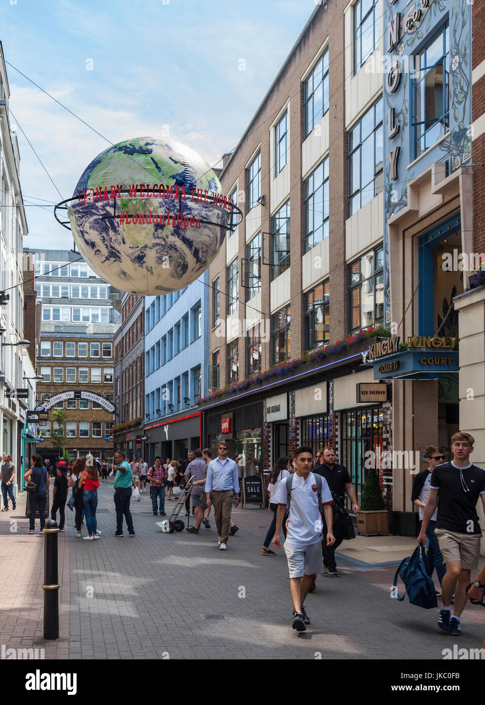 Pedoni in Carnaby Street, Londra, Regno Unito. Grande Globo sospeso con messaggi: Carnaby accoglie favorevolmente il mondo e #LondonIsOpen. Foto Stock