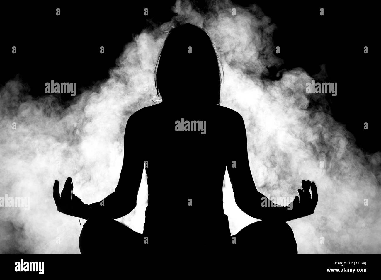 Silhouette di una ragazza la pratica dello yoga con fumo in background Foto Stock