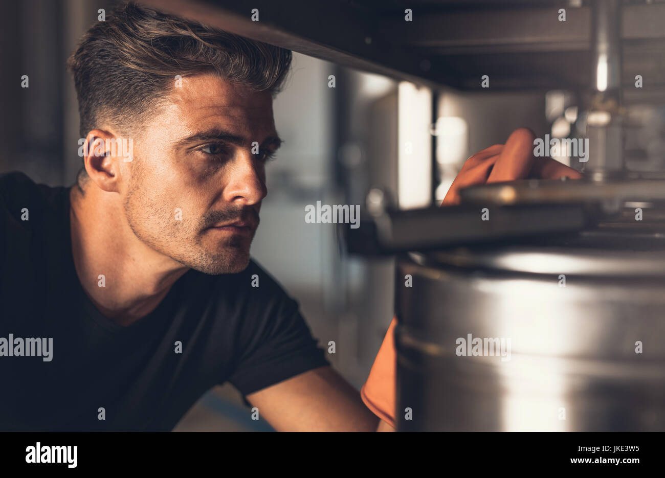 Close up brewer lavora presso la fabbrica di birra. Birraio maschio lavora con birreria attrezzature. Foto Stock