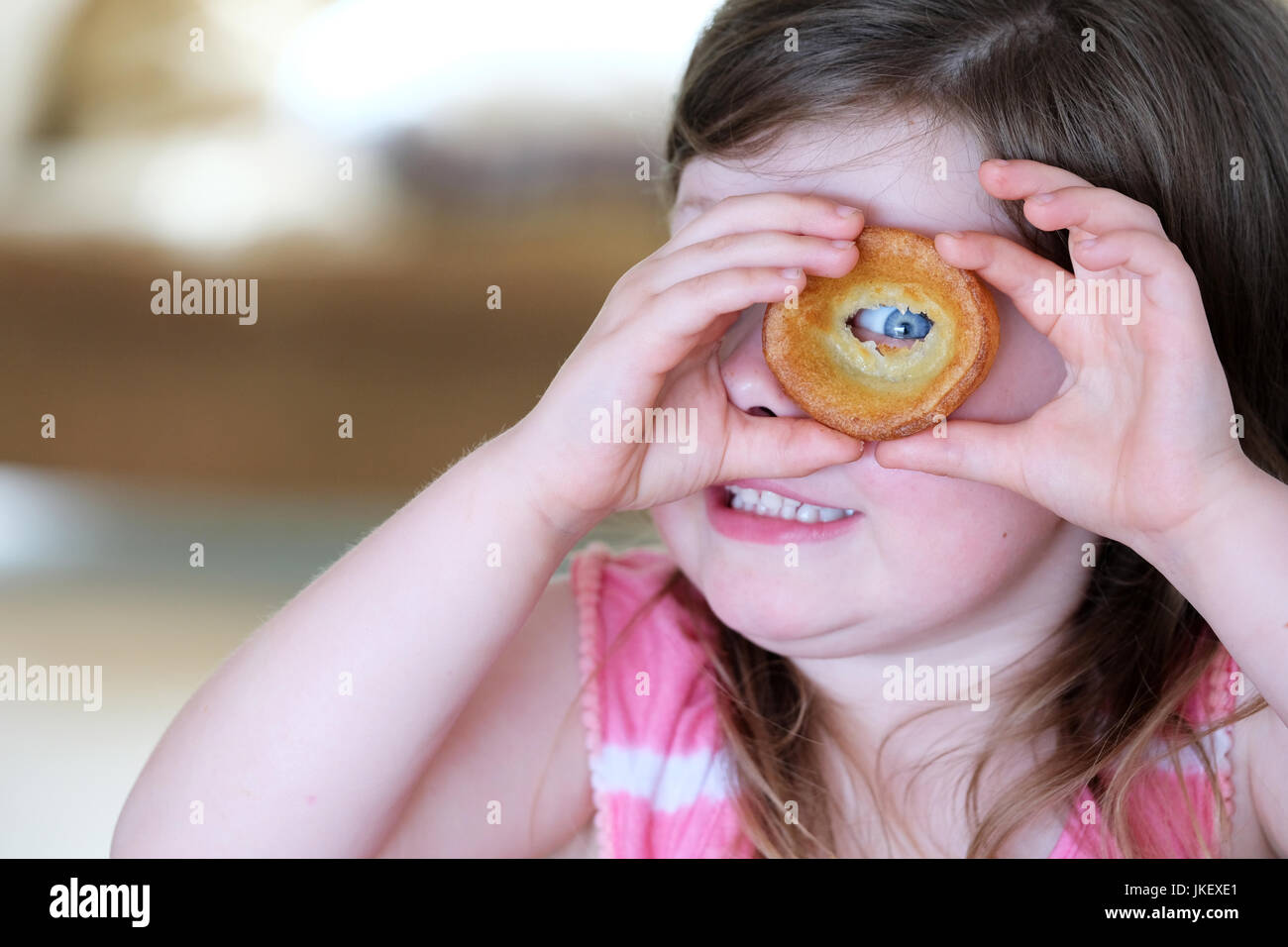Una giovane ragazza guardando attraverso un foro che ha reso in un yorshire pudding mentre si mangia un Arrosto Domenicale cena Foto Stock