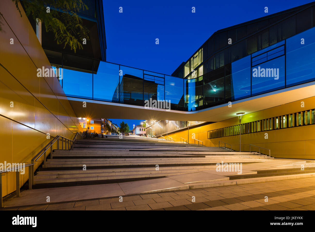 Architettura moderna con un ponte di vetro attraversando un pubblico scala nel centro di Aquisgrana, Germania con night blue sky. Prese con un sistema di spostamento delle lenti per Foto Stock