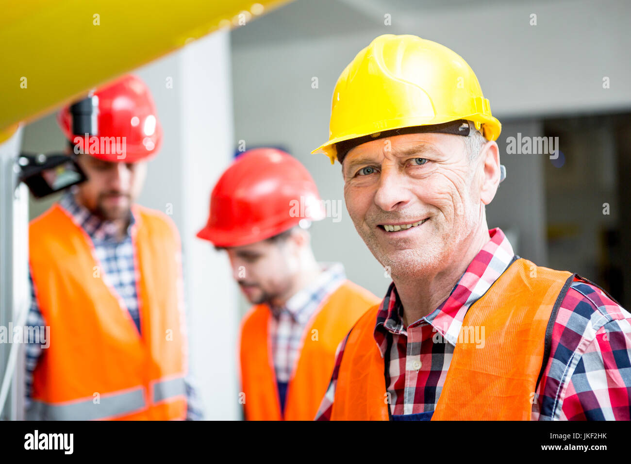 Ritratto di uomo sorridente indossare elmetto in fabbrica Foto Stock
