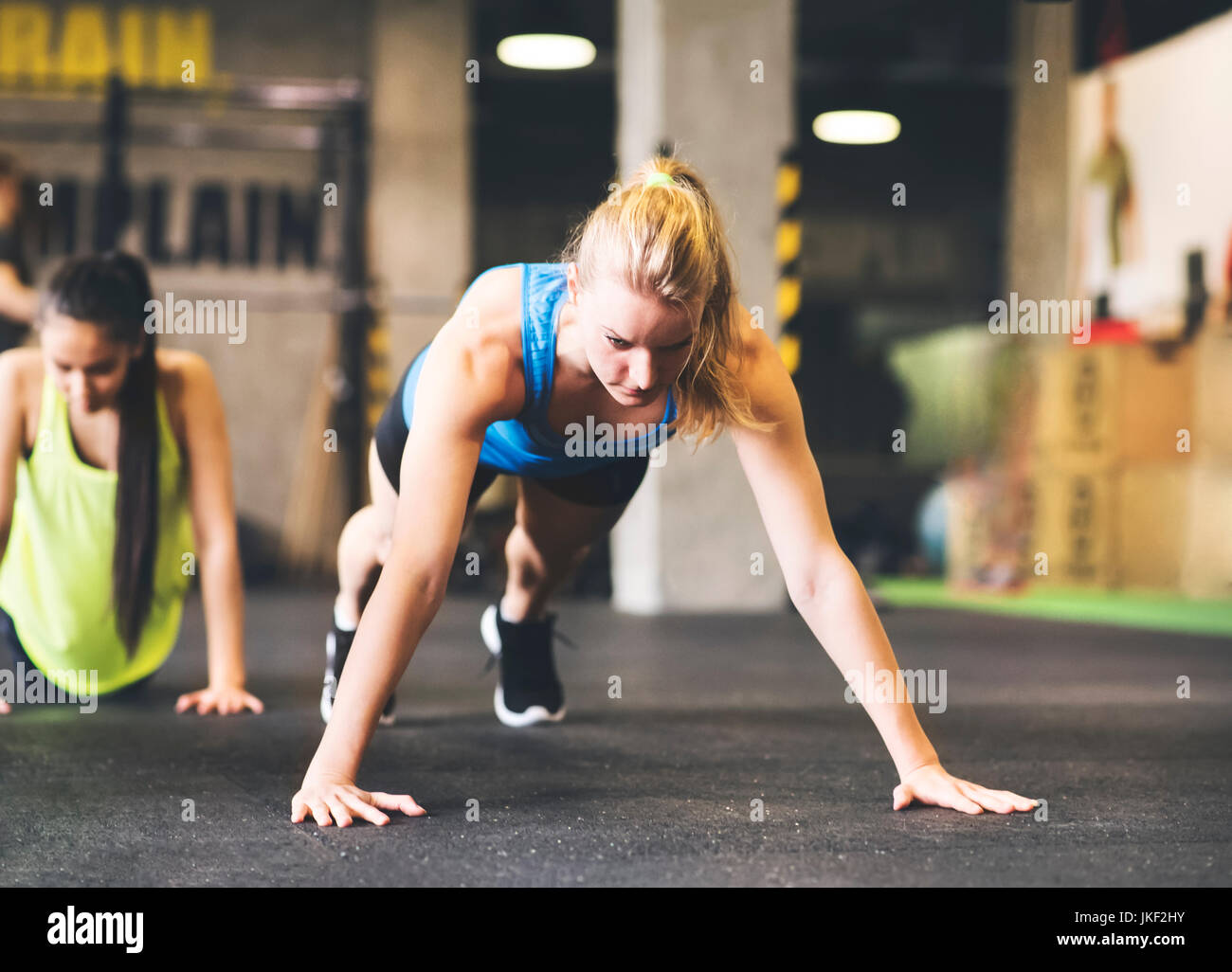 Giovane donna facendo push-up in palestra Foto Stock