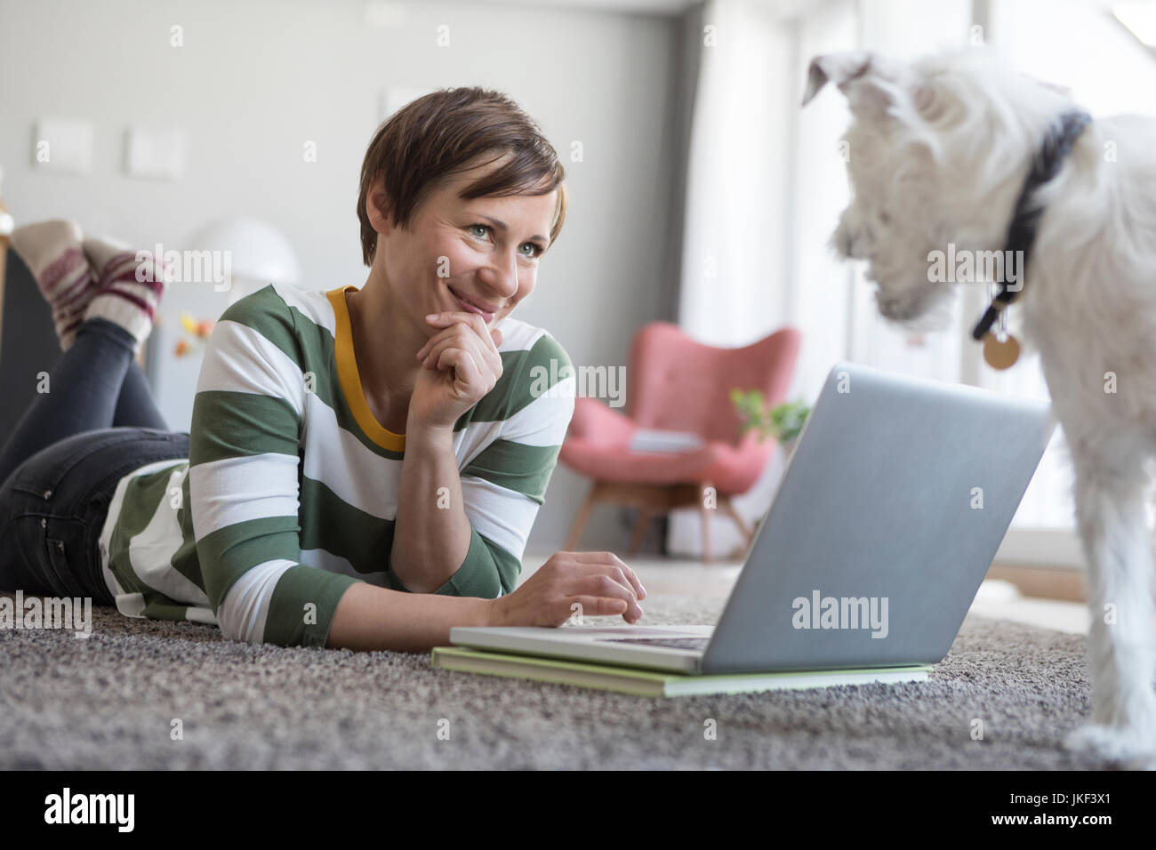 Donna sorridente sdraiato sul pavimento con il computer portatile Foto Stock