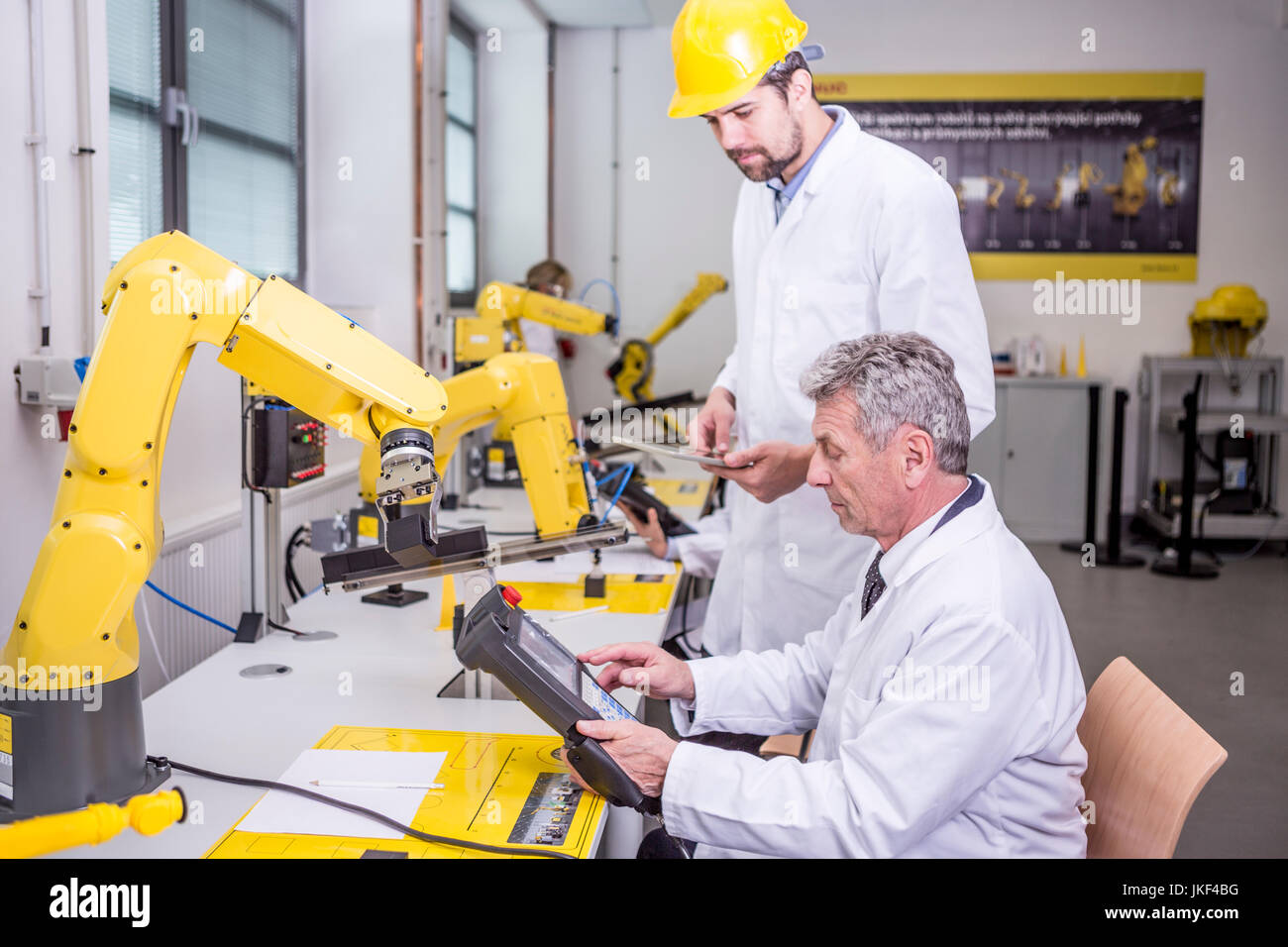 Due ingegneri in fabbrica e guardando il dispositivo Foto Stock