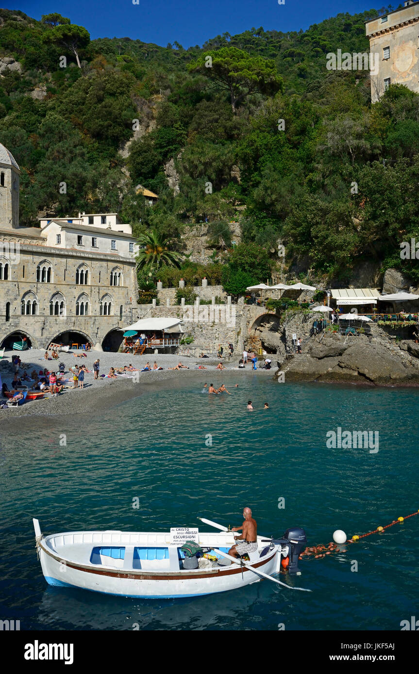 Vista di San Fruttuoso di Camogli, Liguria, Italia, con abbazia medievale, vecchi edifici, mare blu, spiaggia rocciosa e la gente di nuoto Foto Stock
