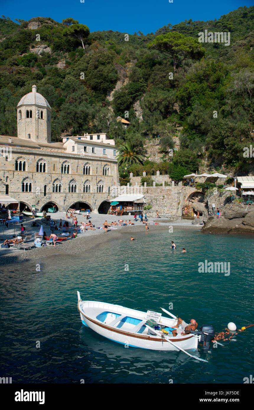 Vista di San Fruttuoso di Camogli, Liguria, Italia, con abbazia medievale, vecchi edifici, mare blu, spiaggia rocciosa e la gente di nuoto Foto Stock
