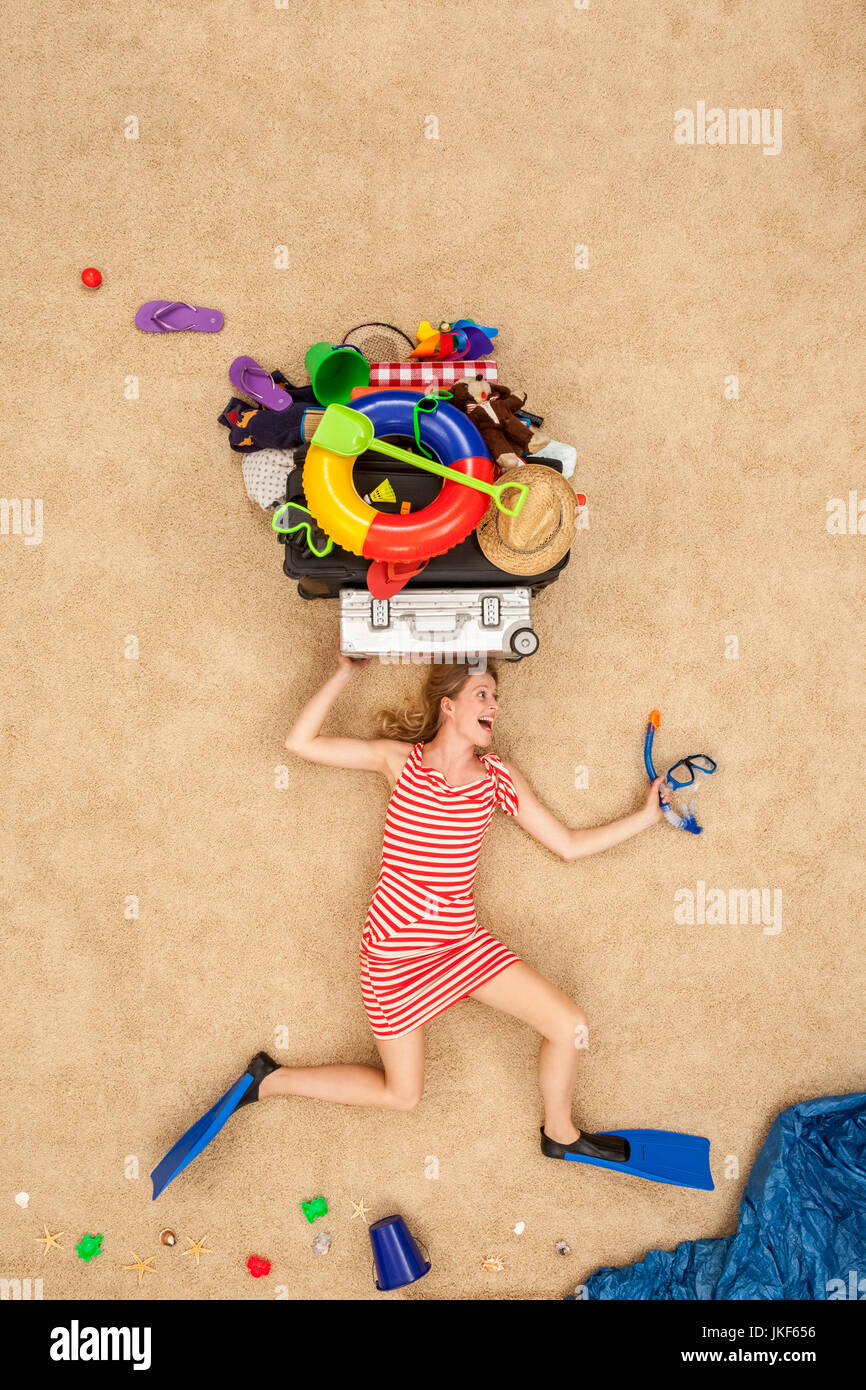 La donna in esecuzione al mare, trasporto di attrezzature per la spiaggia sulla testa Foto Stock