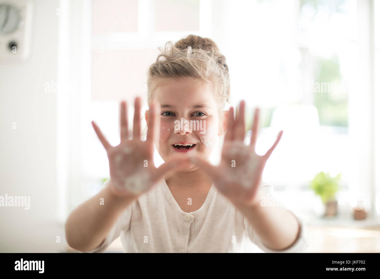 Ritratto di ragazza sorridente in cucina con pasta su mani e viso Foto Stock