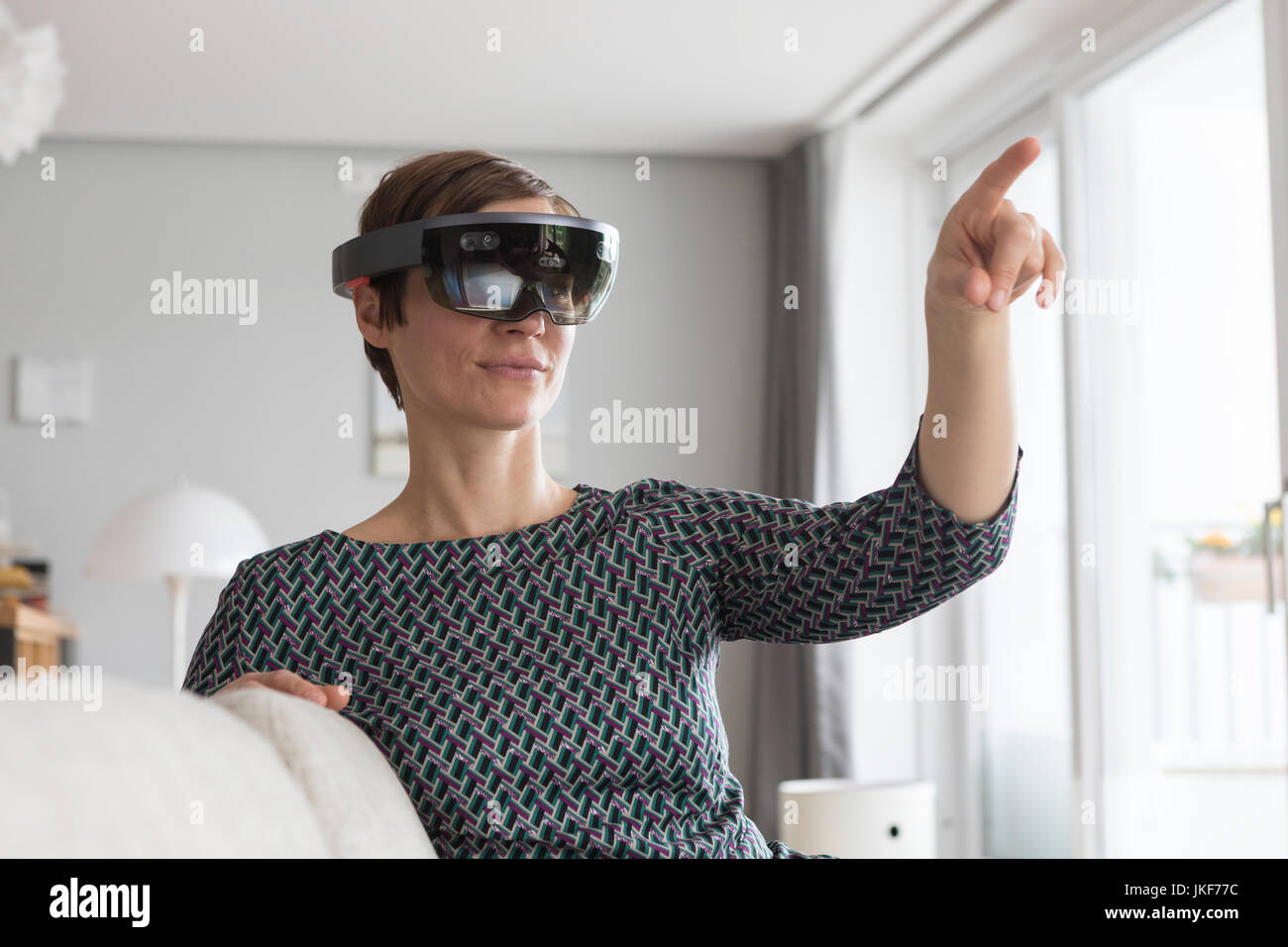 La donna di casa utilizzando la realtà aumentata bicchieri a casa Foto Stock