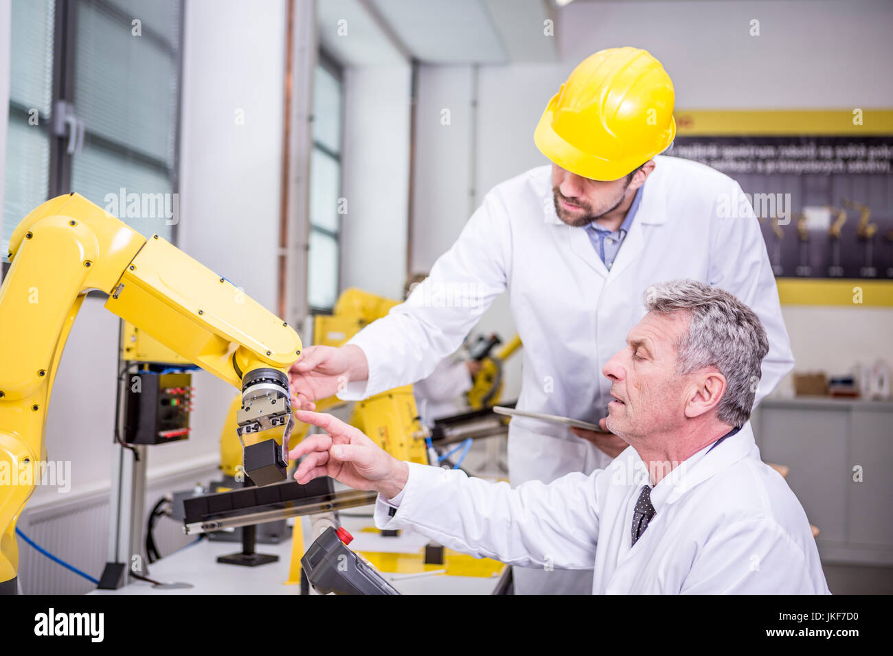 Due ingegneri esaminando robot industriale Foto Stock