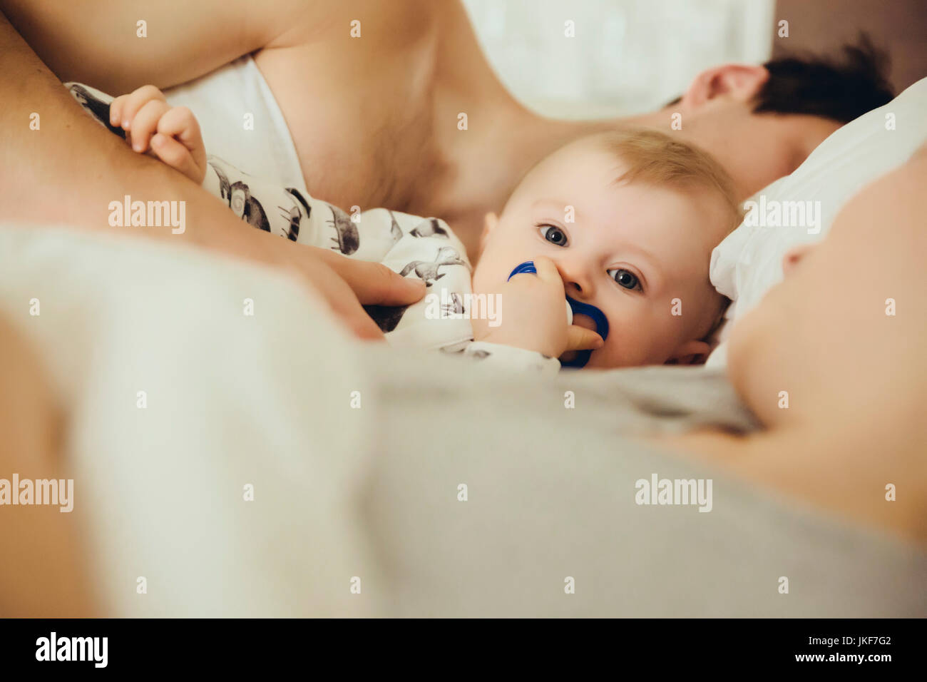 Baby boy cuddling con i genitori in letto Foto Stock