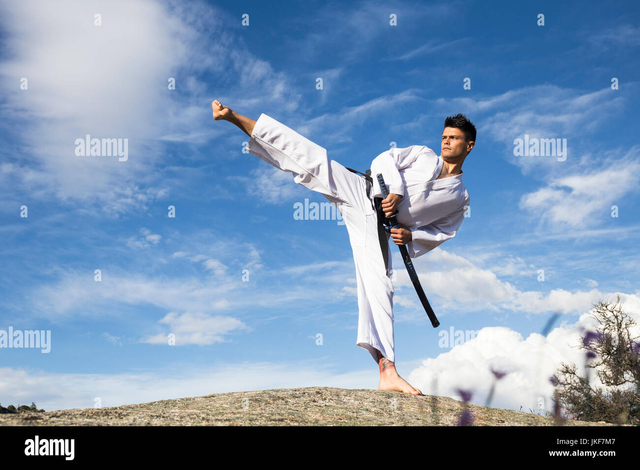 Uomo con una spada katana facendo un calcio alto Foto stock - Alamy