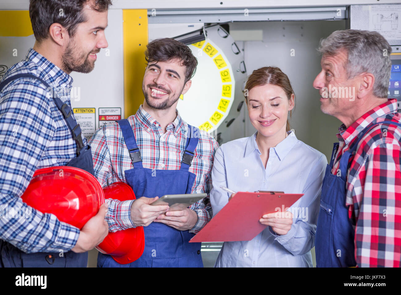 Un personale sorridente in fabbrica con macchine cnc in background Foto Stock
